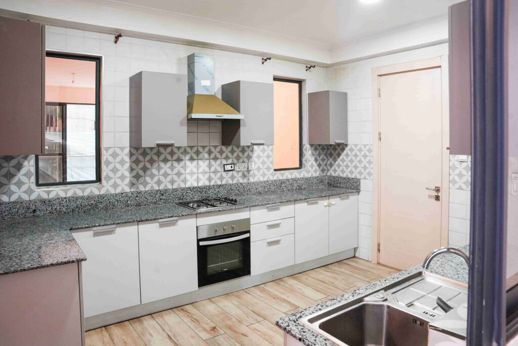 Fitted kitchen with gas hob, oven, patterned tile splashback and granite worktops at 5th Park Heights