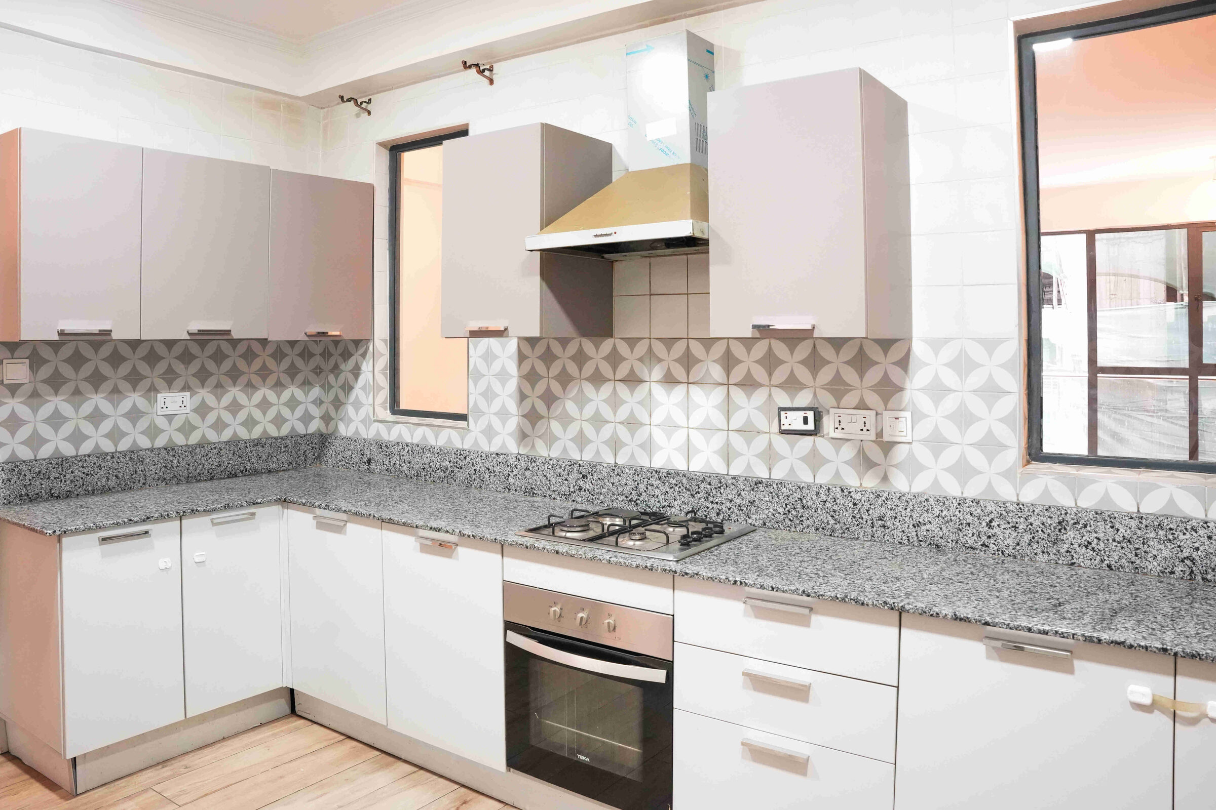 Fitted kitchen with white cabinets, granite worktops and patterned tile splashback at 5th Park Heights