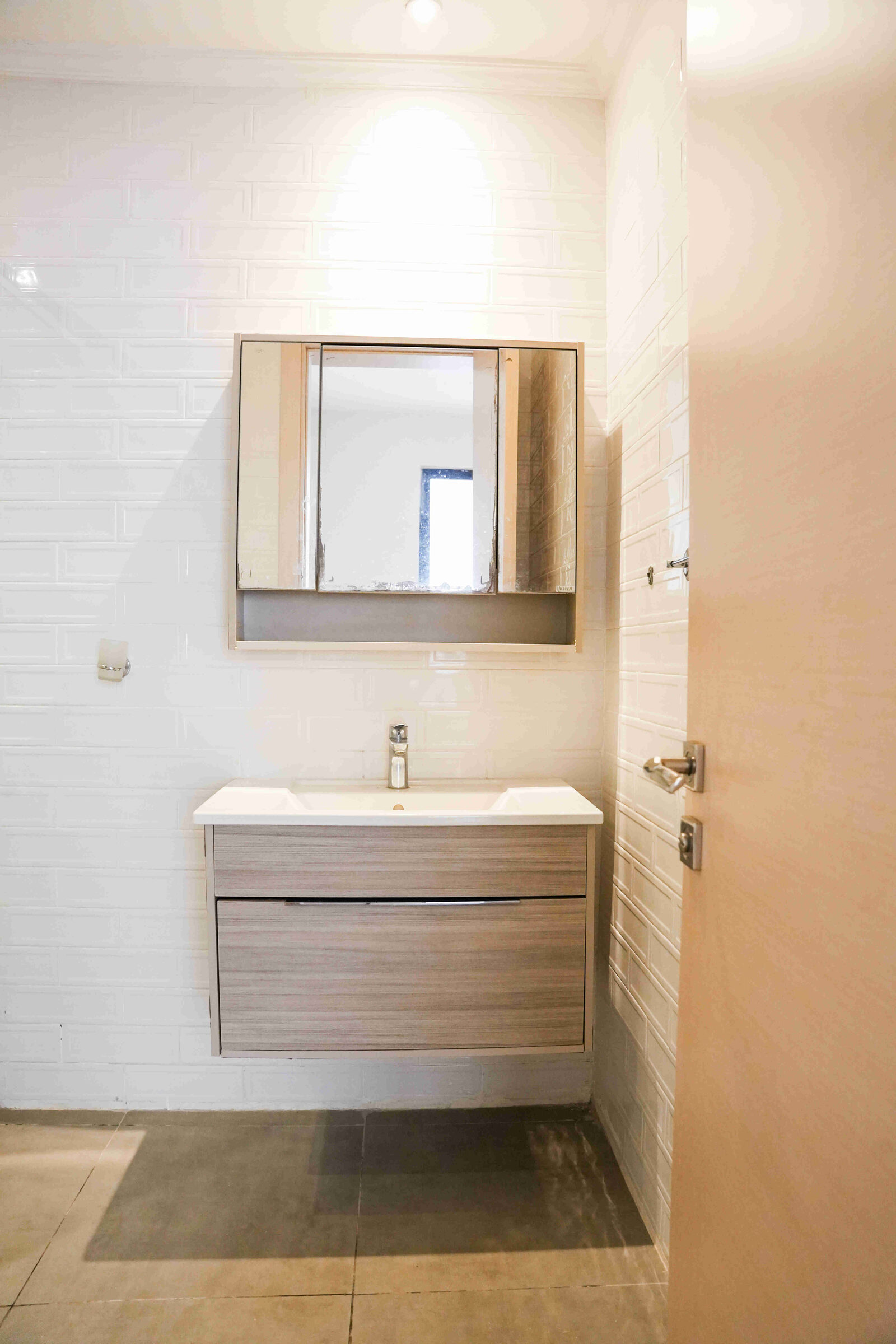 Wall-hung vanity unit with mirror cabinet and white subway tiles at 5th Park Heights