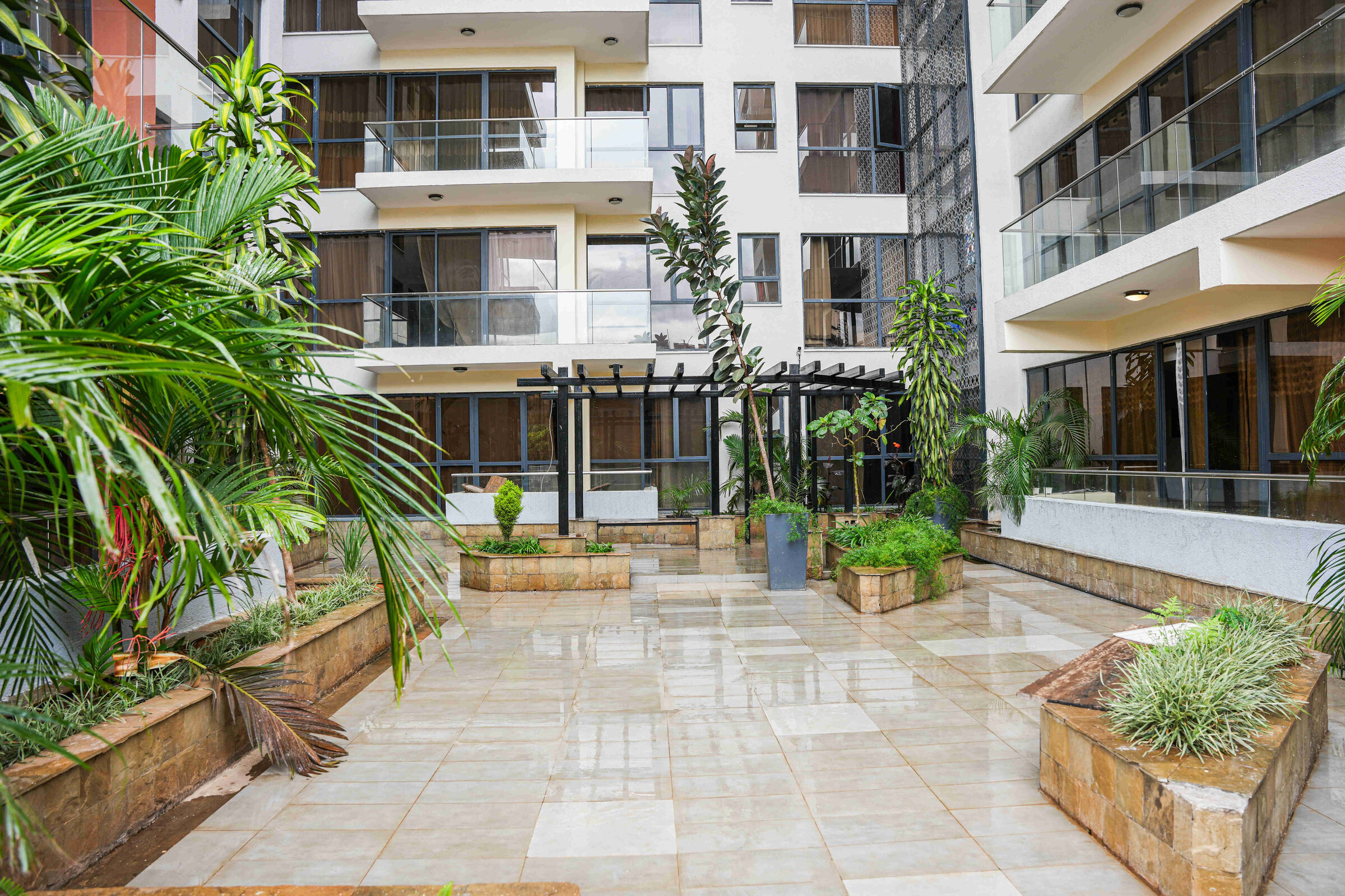 Paved courtyard with raised stone planters and tropical planting at 5th Park Heights