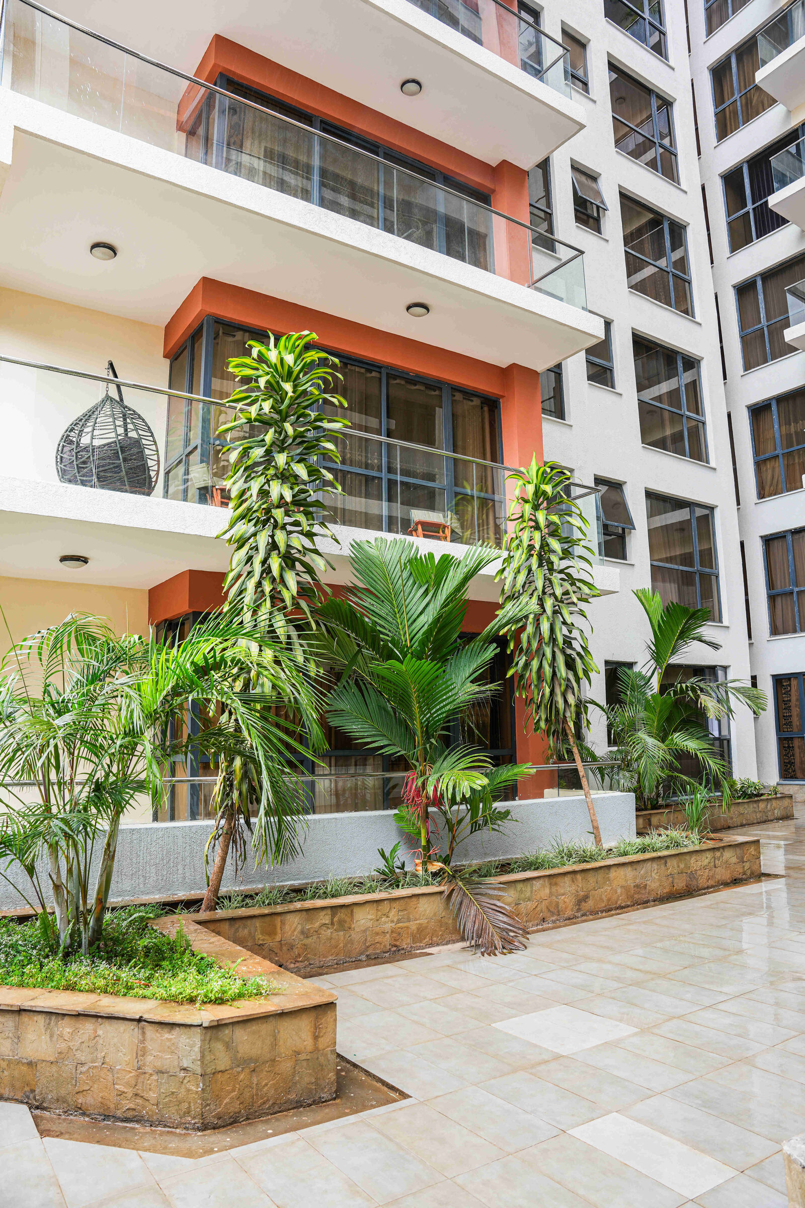 Courtyard garden with tropical planting and building balconies at 5th Park Heights